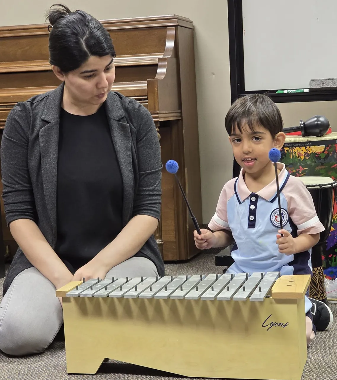 Child exploring a musical instrument with a guest visitor